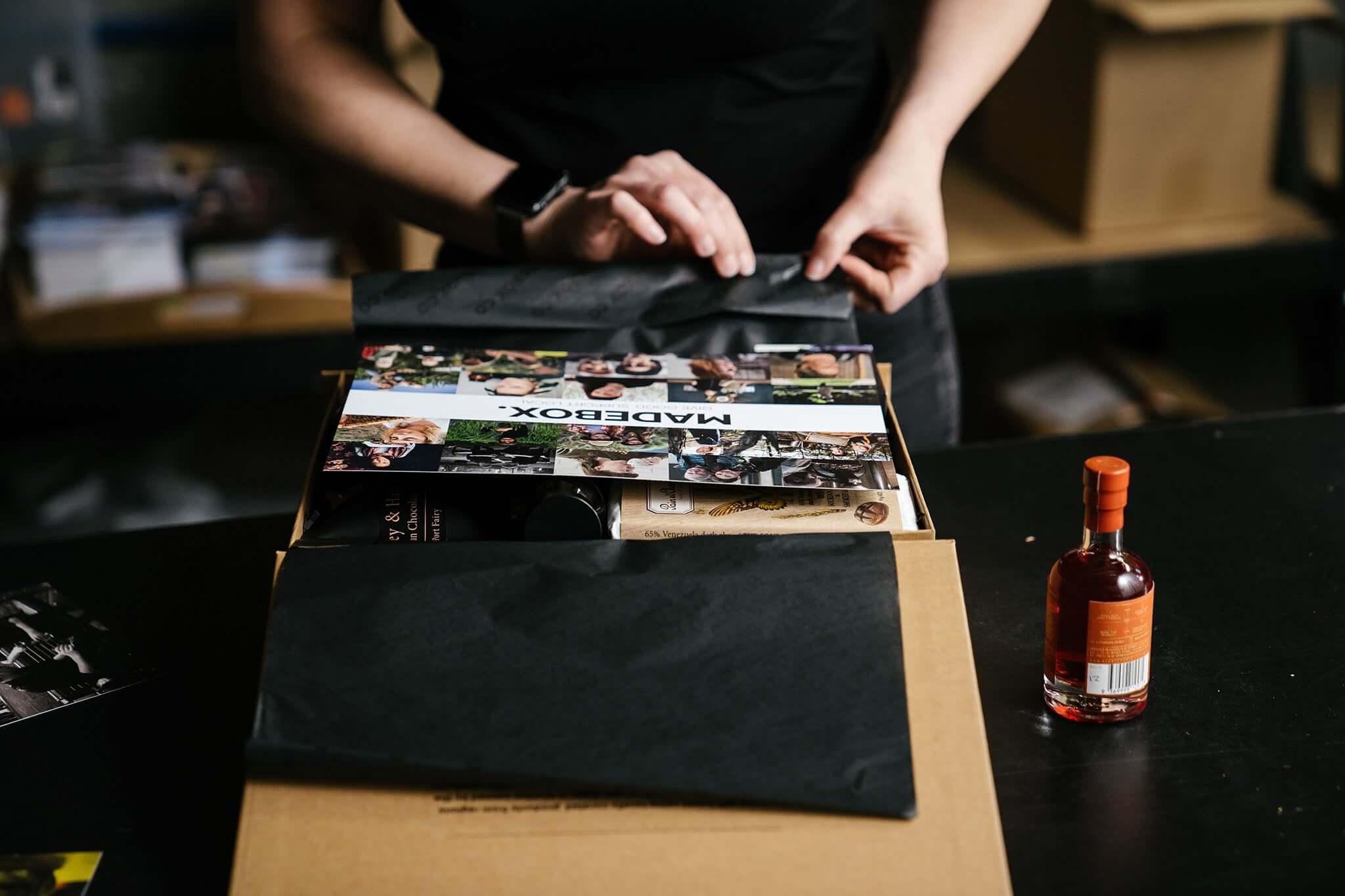 Person packaging The Entertainers gift box from Madebox with custom prints and a gourmet selection.