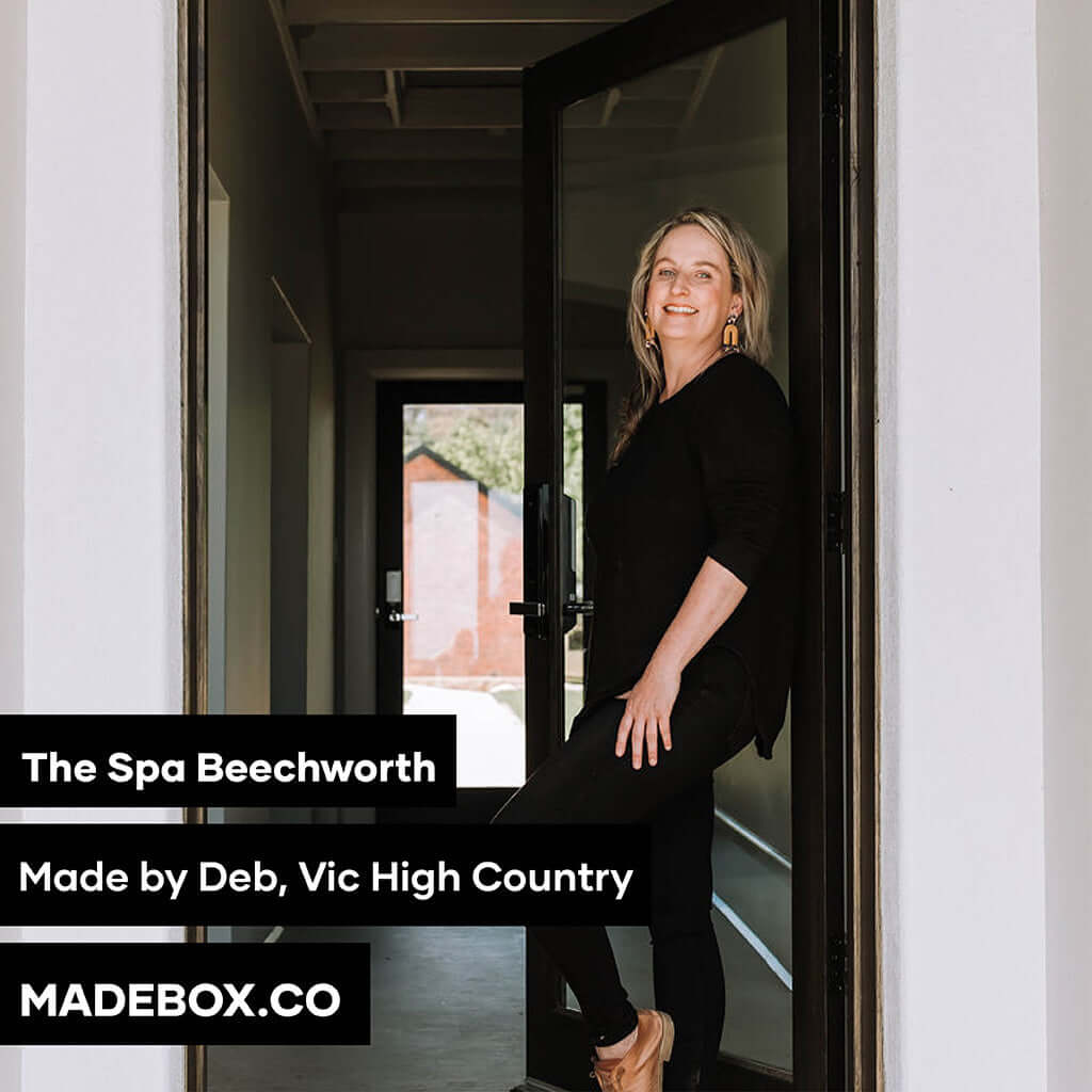 Smiling woman at the entrance of The Spa Beechworth, promoting relaxation with Made by Deb products.