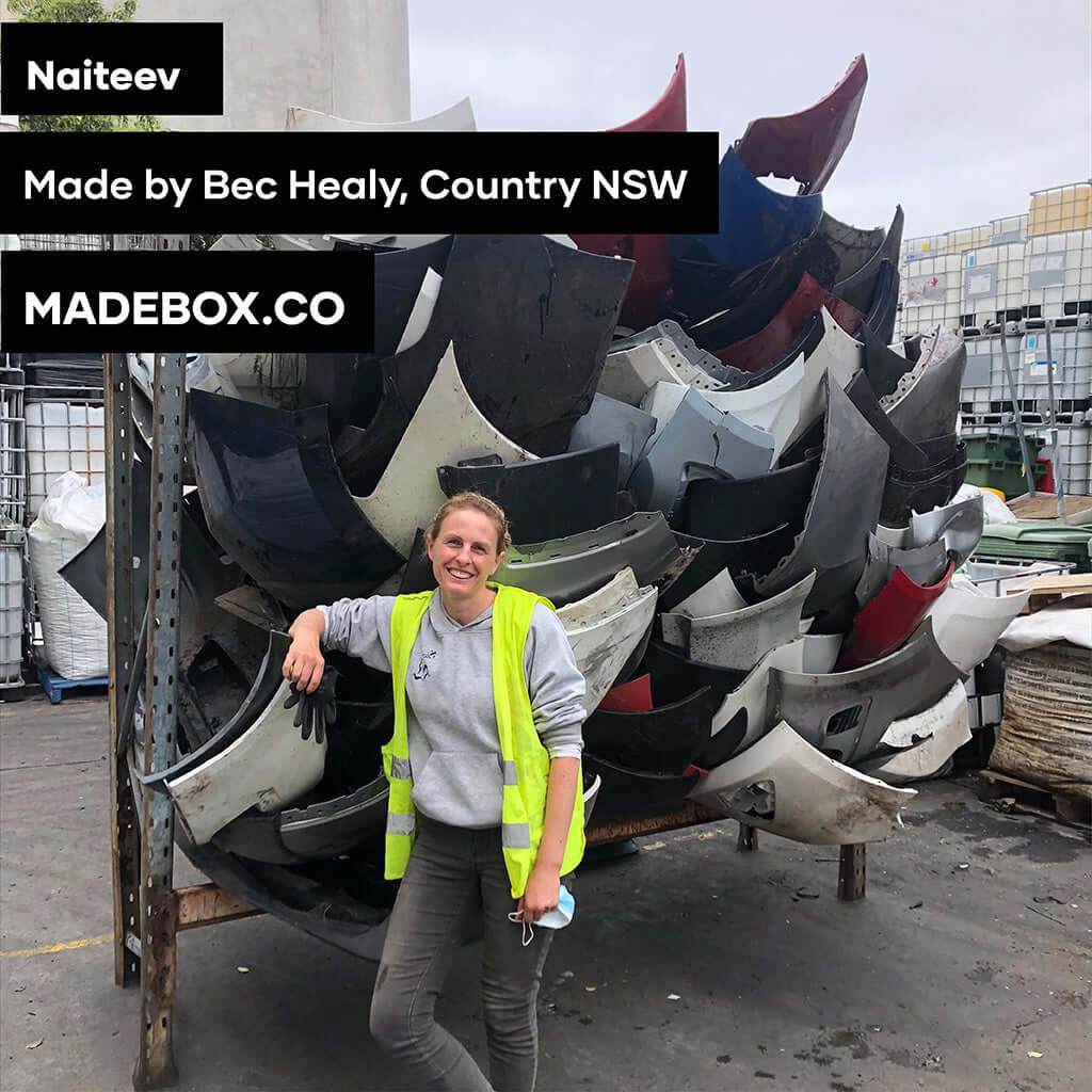 Bec Healy stands beside a stack of recycled materials in Country NSW, showcasing Naiteev's sustainable craftsmanship.
