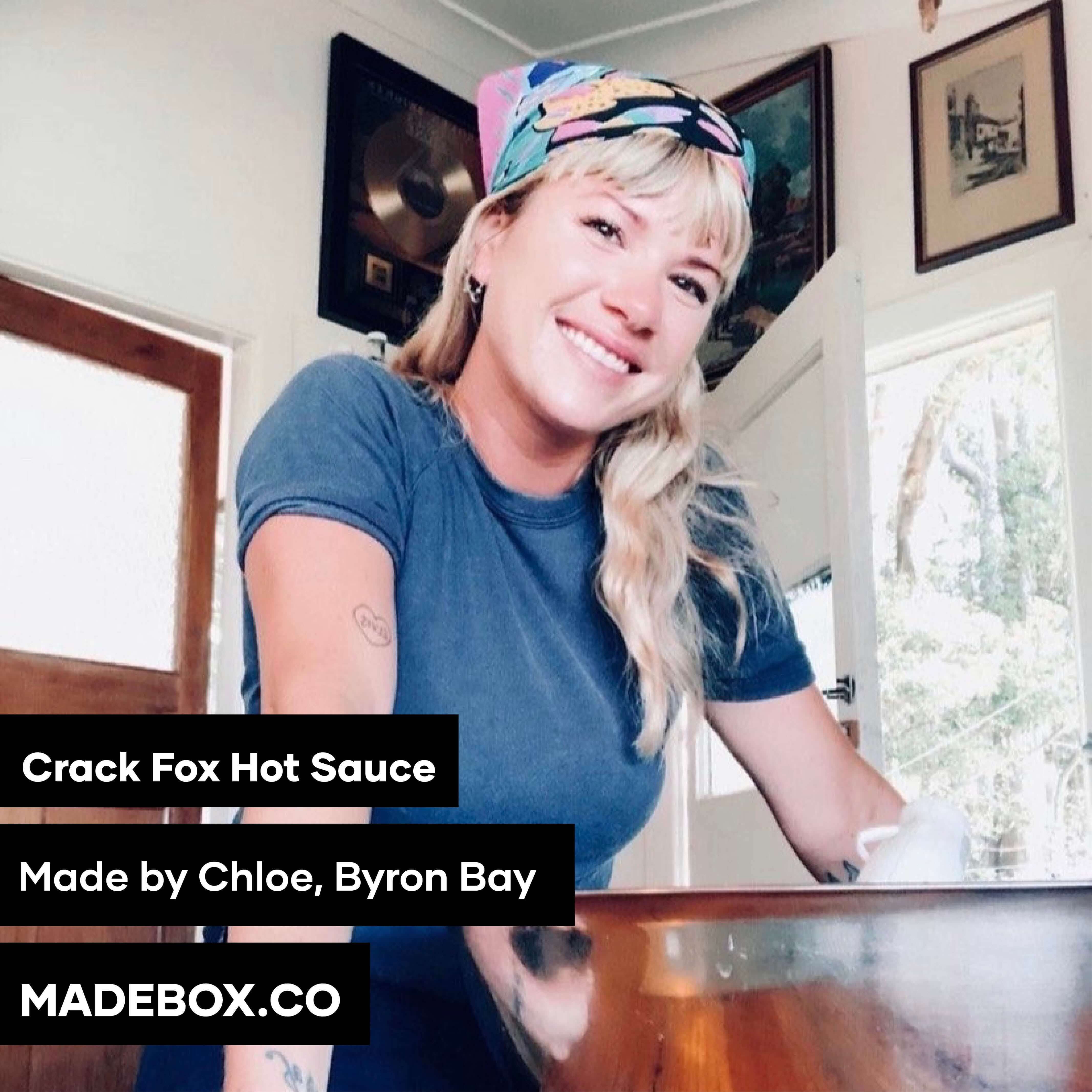 Smiling woman in Byron Bay showcasing Crack Fox Hot Sauce, crafted by Chloe with fresh ingredients.